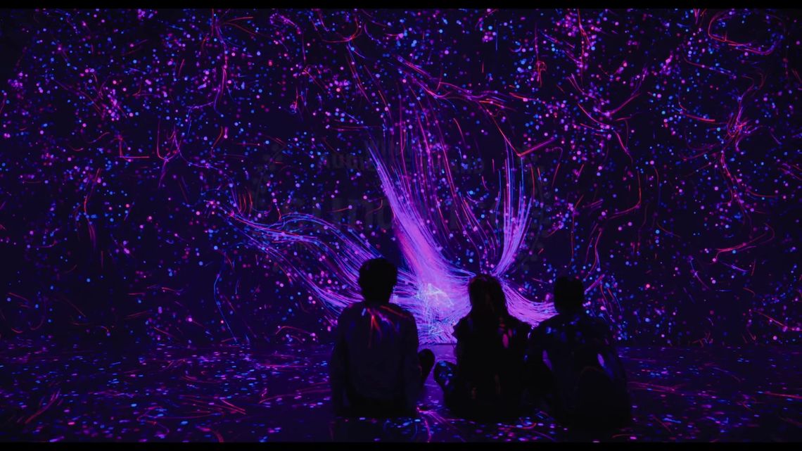 Three characters seated amid purple and pink projections in Quantum Trampoline.